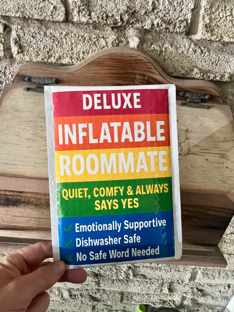 Canada Gag Gift. Close up of a Deluxe Inflatable Roommate novelty sticker featuring a rainbow design and humorous roommate benefits.