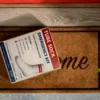 Photorealistic image of the “Tube Sock Emergency Kit” prank mail label designed to resemble legitimate over the counter packaging. The label is displayed leaning against a red front door to mimic real-world delivery, reinforcing the believable and high-impact presentation of this anonymous gag gift.