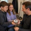 Son and daughter giving their dad a personalized hockey puck marked To Dad, From the Kids, with Best Dad Ever written around the side.