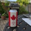 Canadian flag beer can sleeve on a backyard patio table beside a barbecue