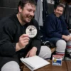 Beer league hockey player laughing while holding a Best Chirper hockey puck beside an opened mailer and reveal card.