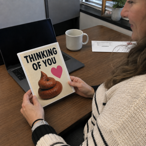 Woman opening a funny Thinking of You prank mailer at her desk