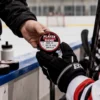 Coach handing a Player of the Game hockey puck award to a young player on the bench