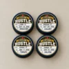 Heart & Hustle Hockey Puck Stickers - Completed Awards Four hockey pucks with navy and gold Heart & Hustle stickers filled in with player names, dates and opponents.