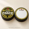 Hockey Coach Thank You Puck Stickers - Front and Back Mockup Product mockup of two black hockey pucks showing a Thank You Head Coach sticker on the front and a blank With Thanks sticker on the back. Pucks not included.