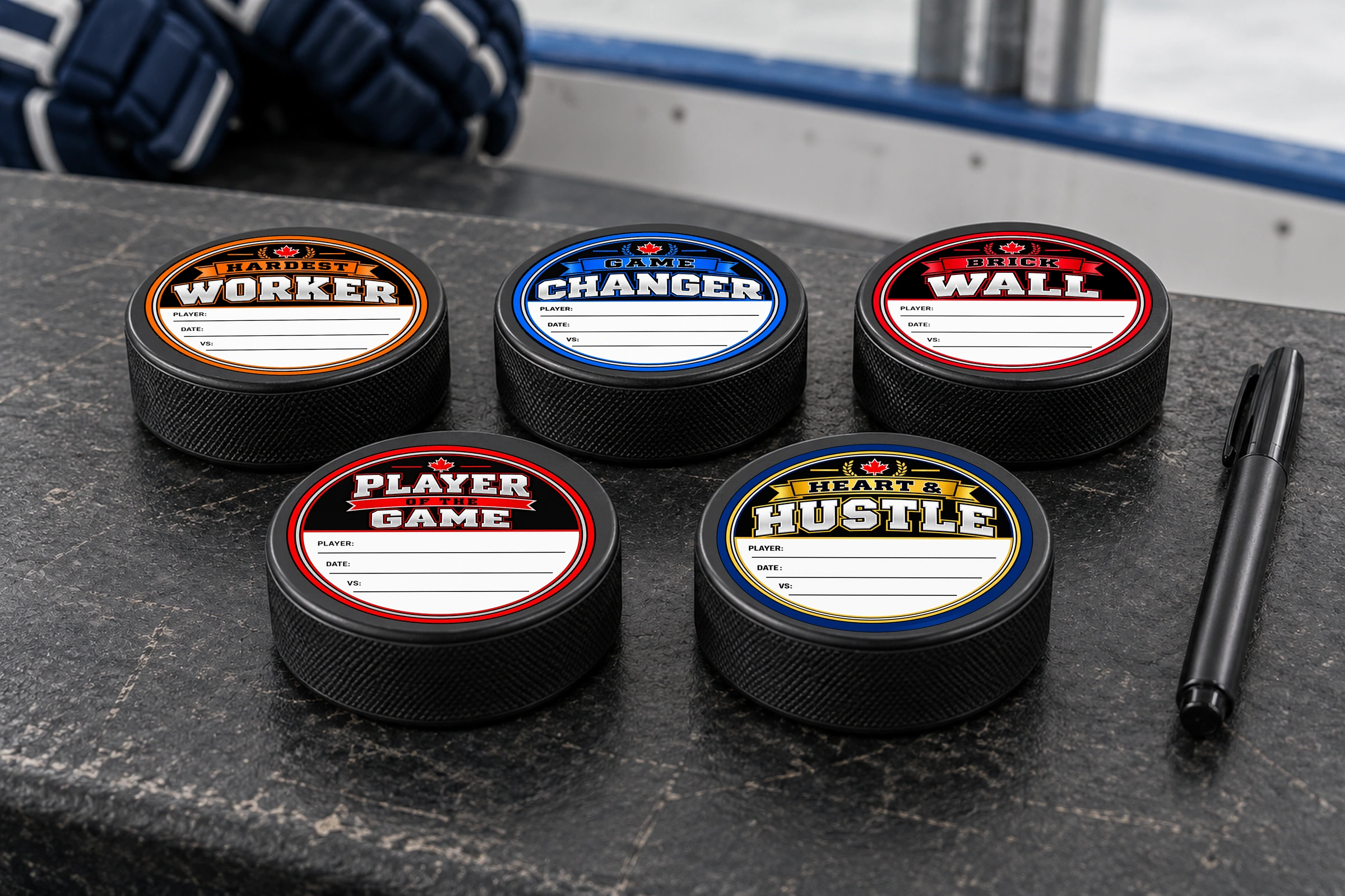 Five hockey pucks displaying Player of the Game, Heart and Hustle, Hardest Worker, Game Changer and Brick Wall stickers